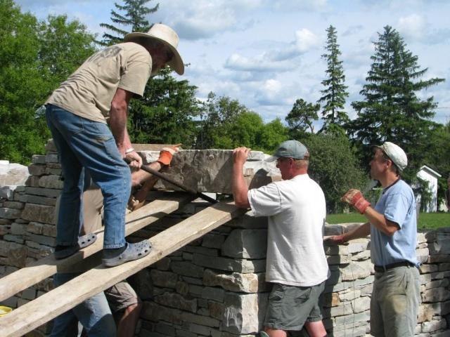 Eric and Evan and John struggle to maneuver a big stone into position